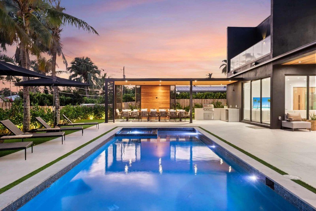 A finished backyard pool at dusk — lights on, ready to enjoy